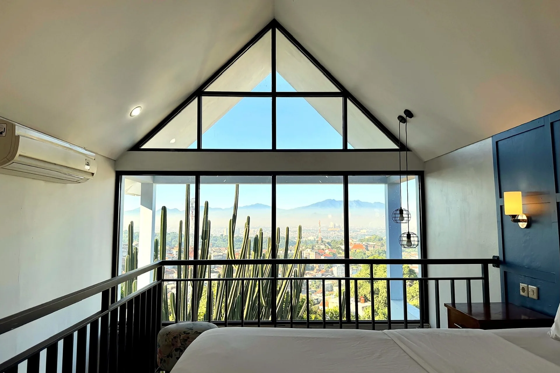 Mezzanine bedroom with pitched triangular windows, cactus garden and panoramic Bandung city and mountain views
